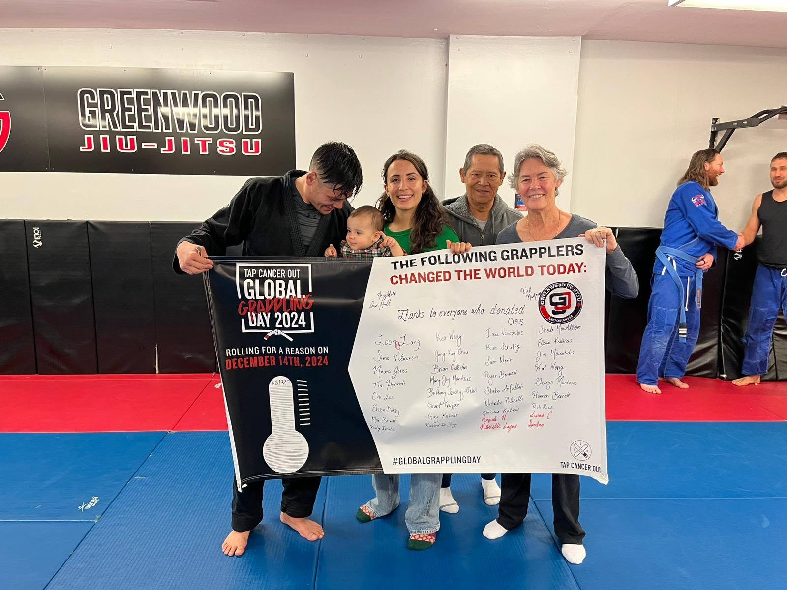 Global Grappling Day supporters holding a signed campaign board