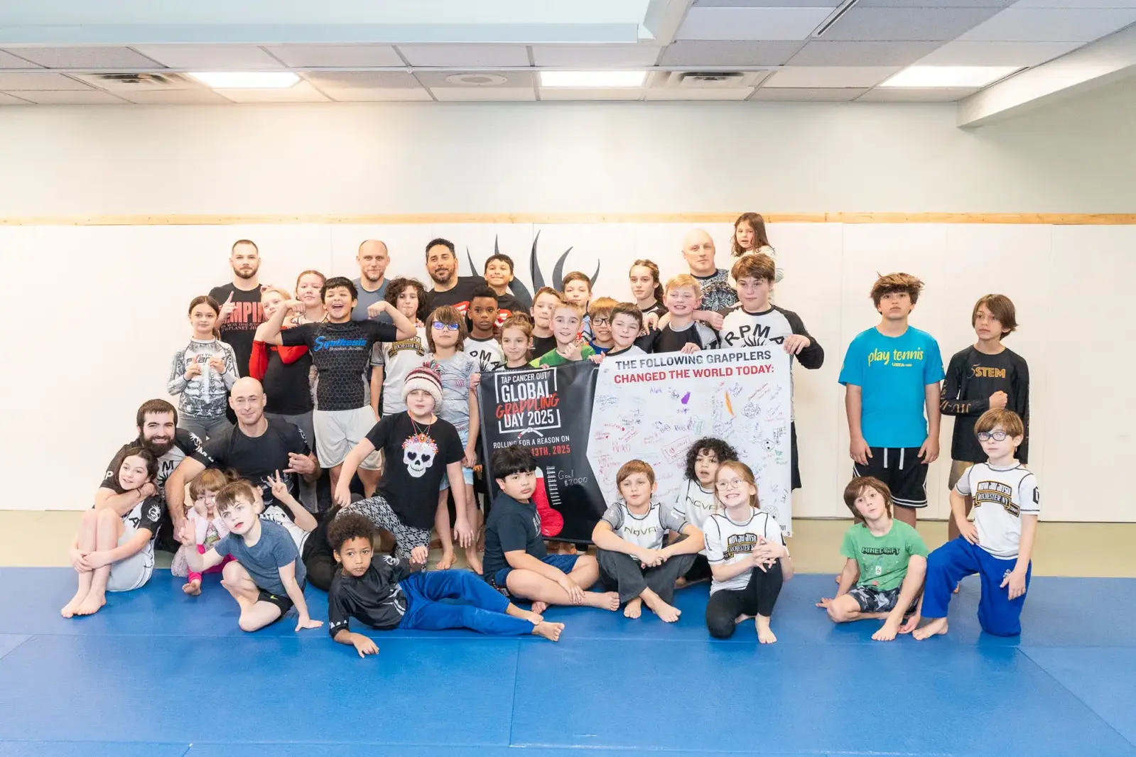 Young grapplers gathered around a Global Grappling Day board